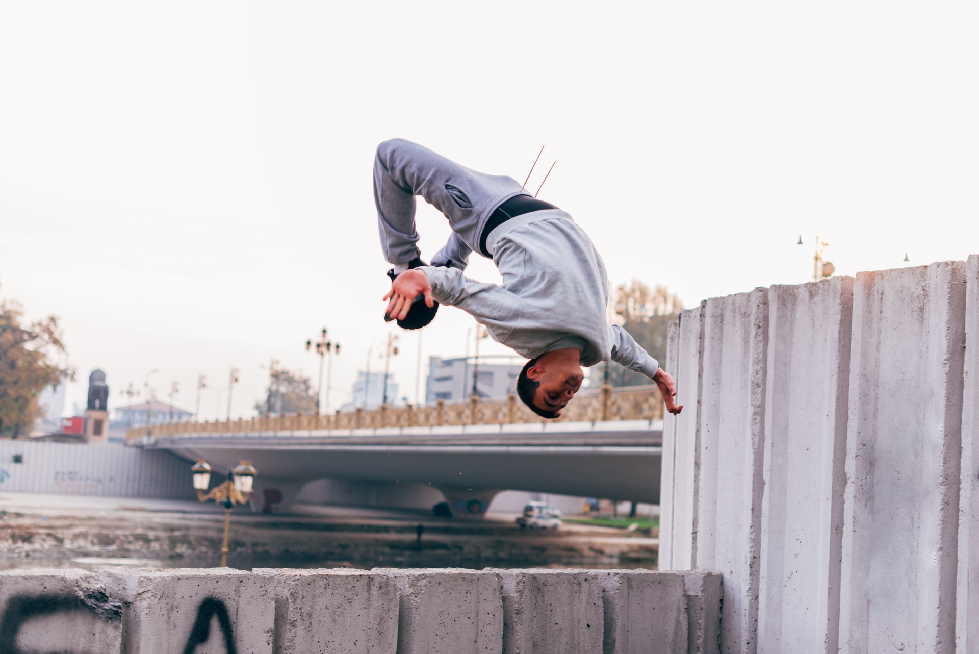 Young man practicing parkour at the city park,doing tricks and jumps.